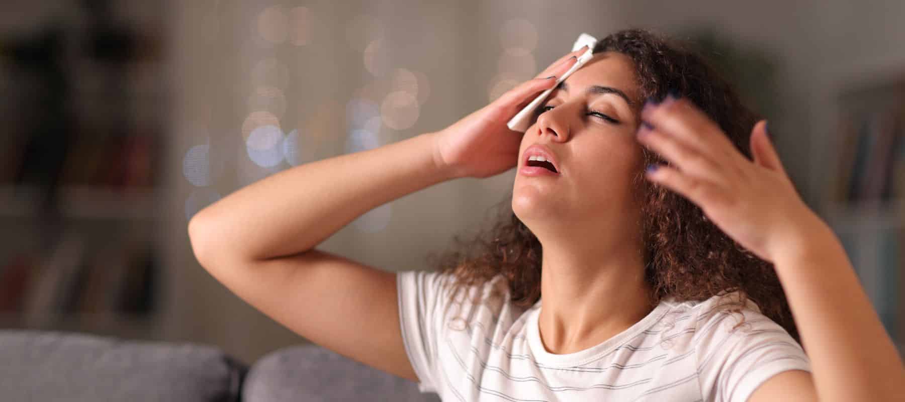 woman showing stress and fatigue as she sits in her home with an AC that is blowing hot air