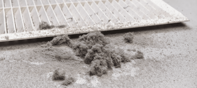 closeup of a cluster of dust that has accumulated sitting next to an hvac vent